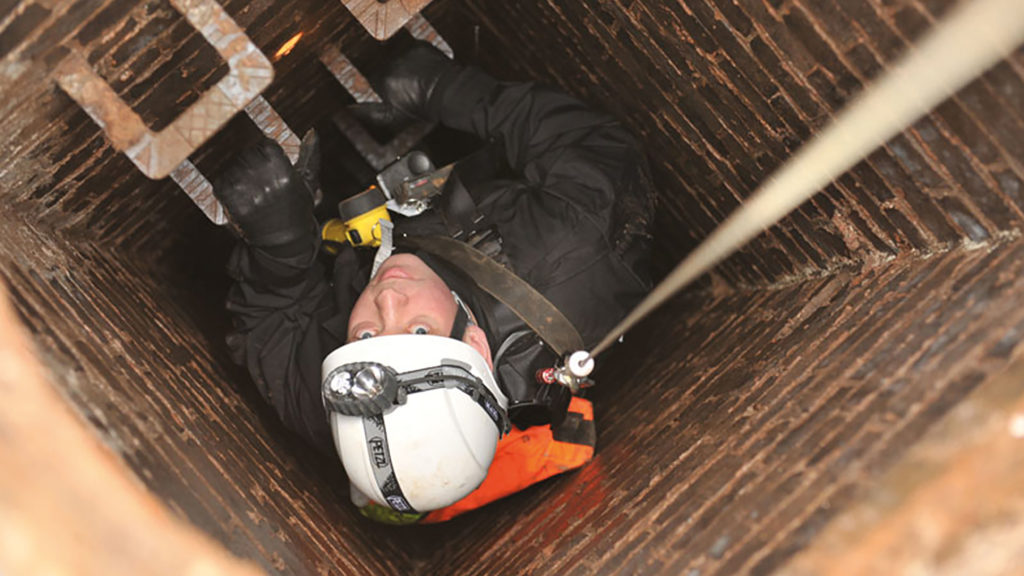 MDP search officer, using rope access, in a hole in the ground