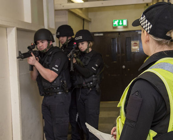 MDP Firearms Instructor with officers training in the background, in a hallway setting