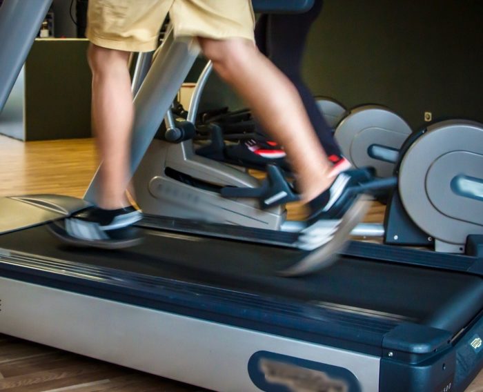 Person running on a treadmill, with only legs and trainers visible